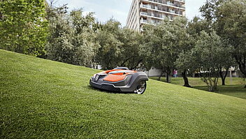 Professional Automower mäht auf einem Hügel einer Parkanlage den Rasen.